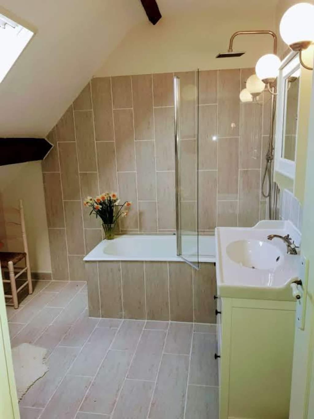 Badewanne unter der Dachschräge, beige Fliesen, ein Blumenstrauß
