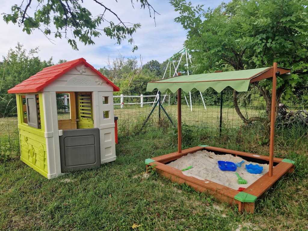 Playhouse and covered sandpit on the lawn, with a swing behind