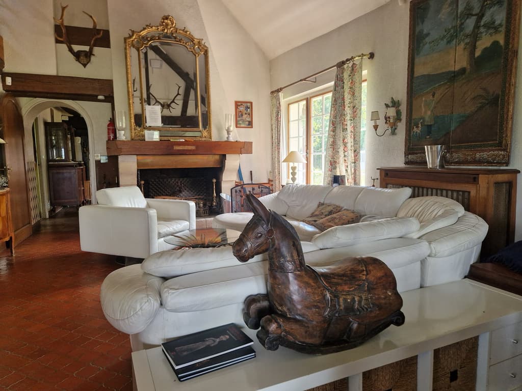 Soggiorno con un cavallo di legno scolpito sul divano bianco, un quadro e il camino