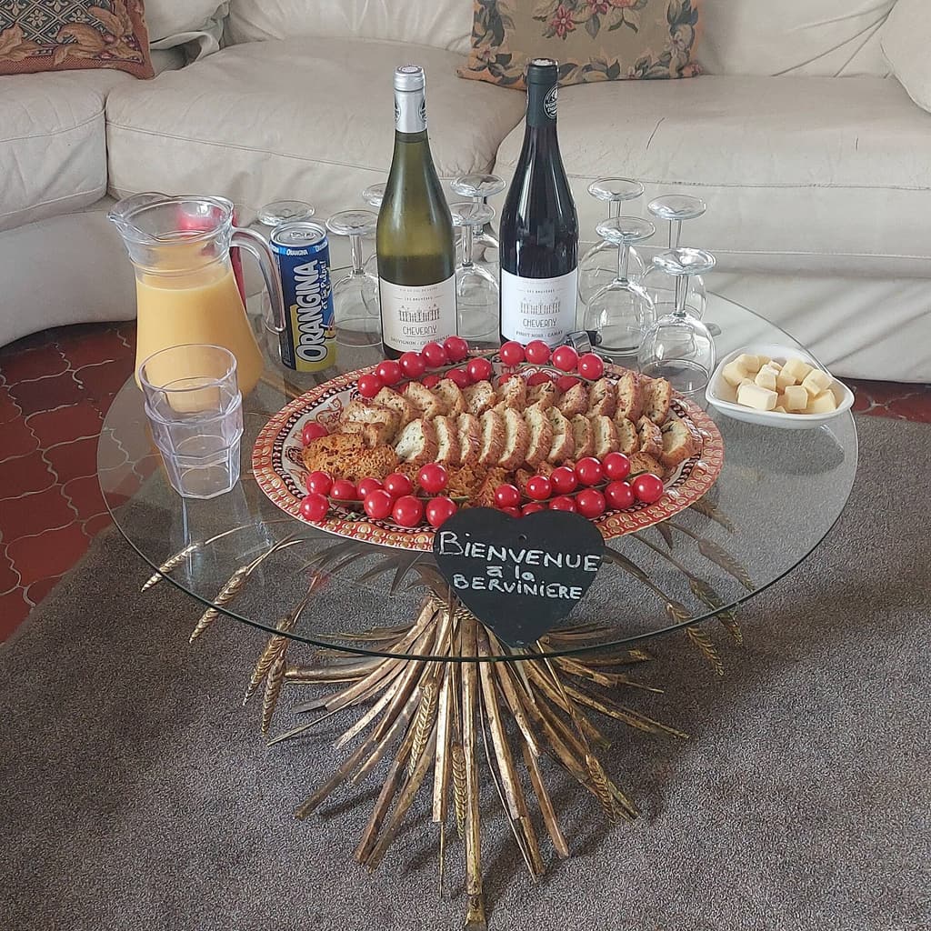 Welcome tray on the coffee table: bottles, juice, cherry tomatoes and a slate reading Bienvenue à la Bervinière