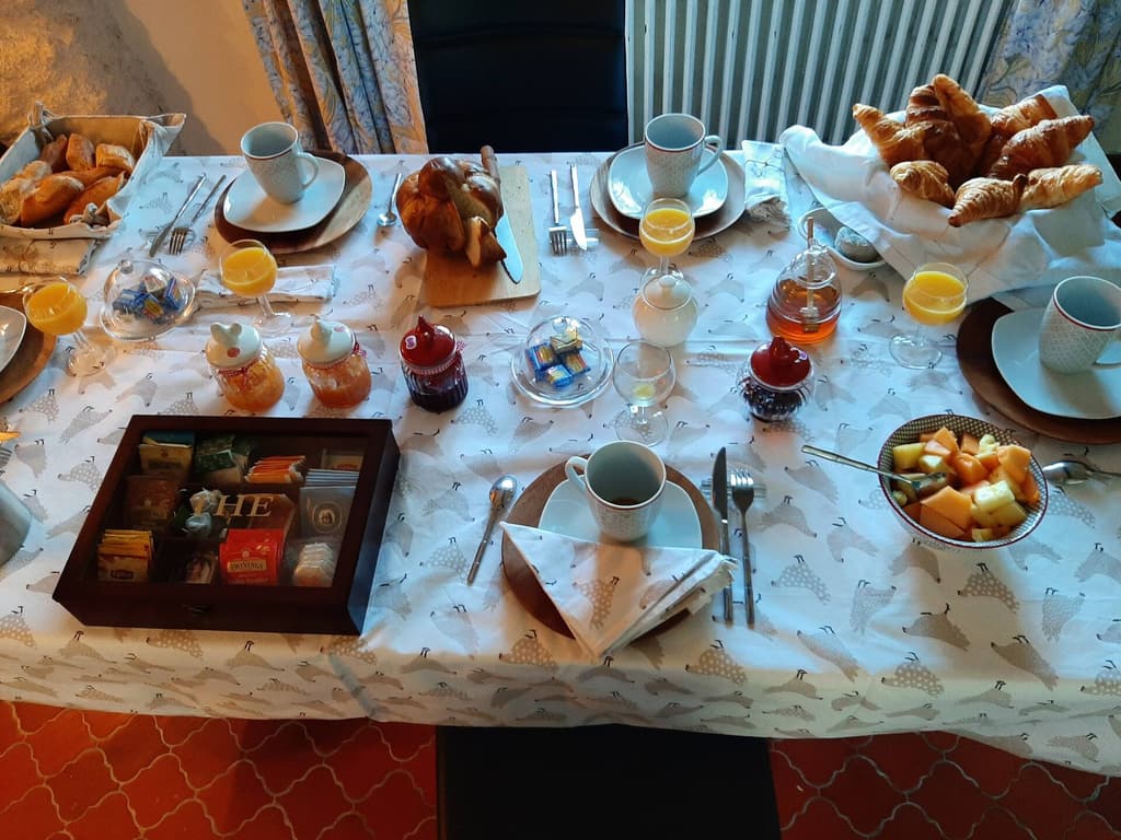 Gedecktes Frühstück mit Croissants, Eiern, Orangensaft, Obst und Tee auf einer gemusterten Decke