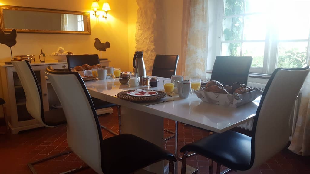 Sala da pranzo al mattino, tavolo bianco, sedie nere, brioche e succhi