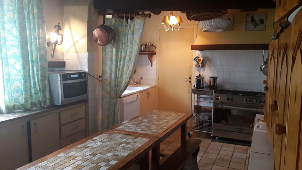 Cucina con fornello a gas, rami di rame appesi e tende a fiori